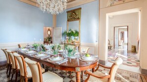 A dining room with a long table set for six, surrounded by six chairs, a chandelier, and a mirror on the wall. - Luxury Villa With Pool in Lucca (Capannori)