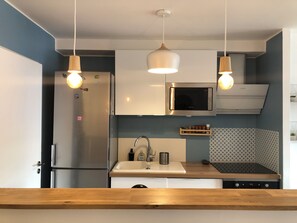 A modern kitchen with a stainless steel refrigerator, a microwave, a sink with a wooden countertop, and pendant lighting. - 🌞🪸 Le Corail 🪸 - Apartment 3 bedrooms 6 people - 🦩 Le Grau Du Roi 🦩🌞 (Le Grau-du-Roi)