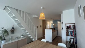 A modern interior with a staircase, a dining area, a kitchen, and a bookshelf. - 🌞🪸 Le Corail 🪸 - Apartment 3 bedrooms 6 people - 🦩 Le Grau Du Roi 🦩🌞 (Le Grau-du-Roi)