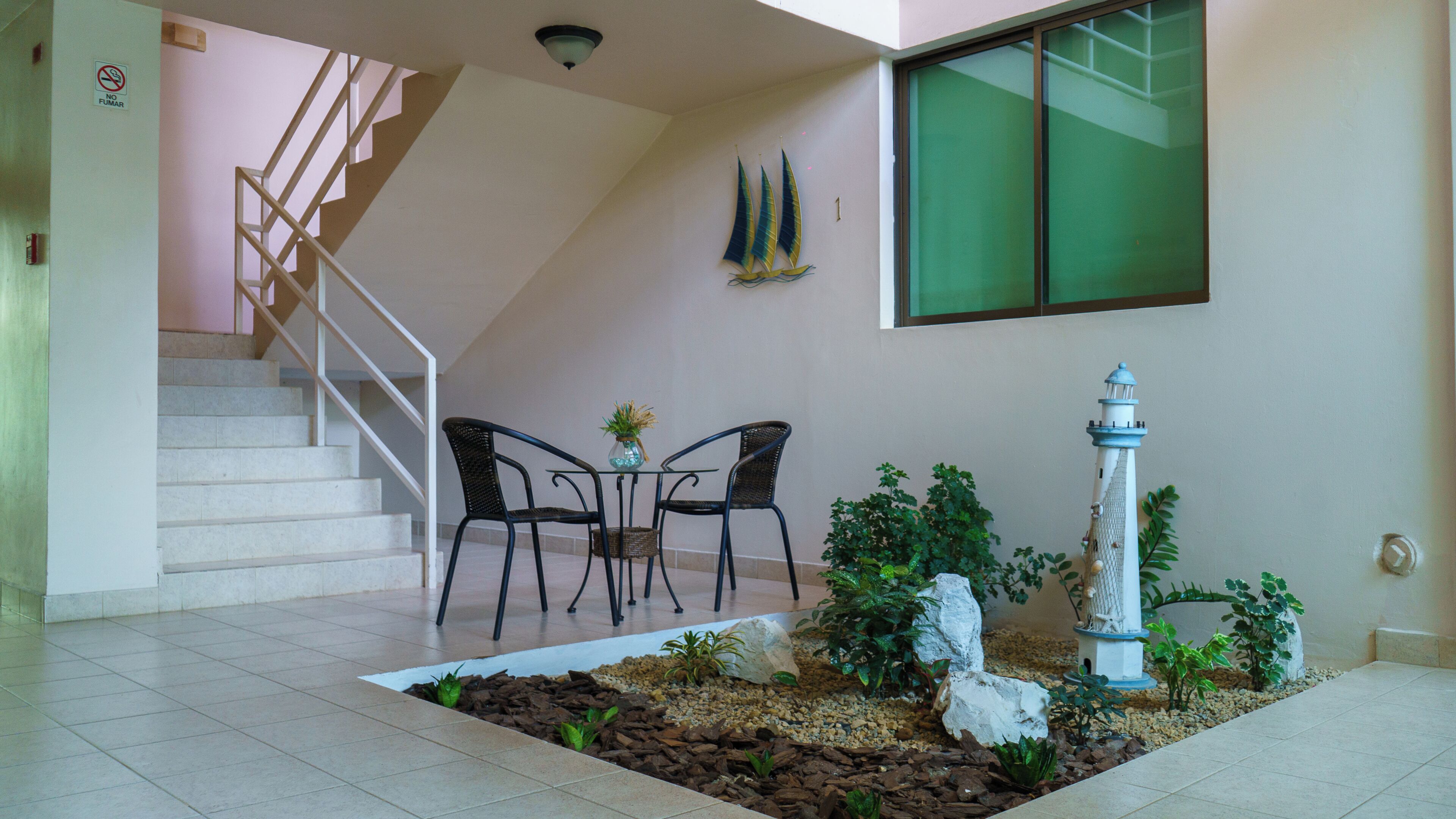 A staircase leading to an upper floor, a small table with chairs, and a decorative garden area with a white statue.