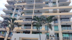 Un hotel de varios pisos con piscina, balcones y unidades de aire acondicionado.