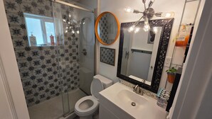 Une salle de bain équipée d’une douche, de toilettes, d’un lavabo et d’un miroir.
