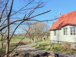 A rural setting with a house featuring a red roof, a clear sky, and a dirt path leading to the house. - 4 Star Holiday Home in Genarp (Hjarnarp)