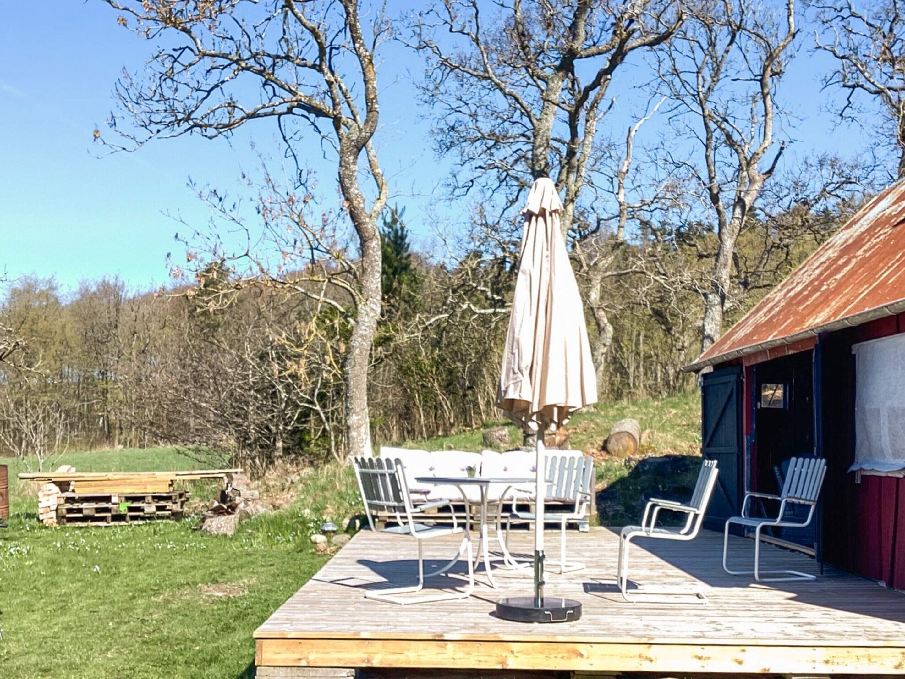 A wooden deck with outdoor furniture, including a table and chairs, and a covered umbrella.