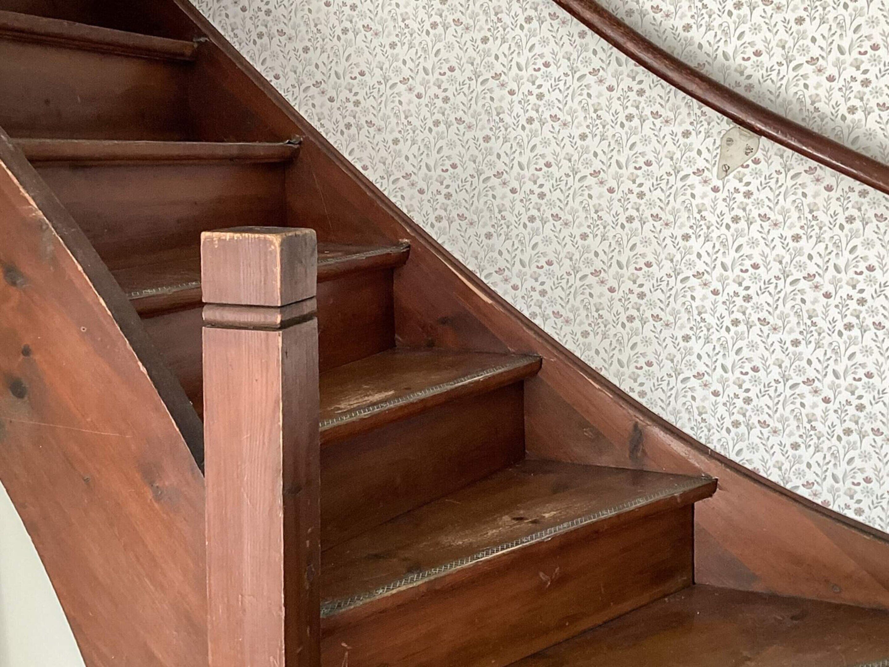 Una scala in legno con carta da parati a motivi floreali.