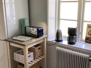 A kitchen with a toaster, kettle, and coffee maker on the counter. There is a window with a view of the outside. - 4 Star Holiday Home in Genarp (Hjarnarp)