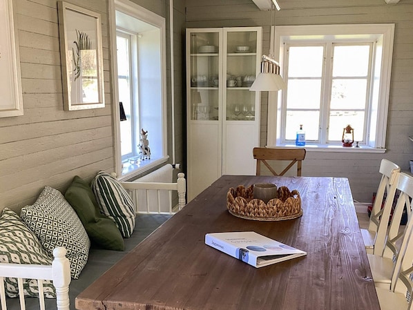 A dining area with a wooden table, chairs, a woven basket, and a book. - 4 Star Holiday Home in Genarp (Hjarnarp)