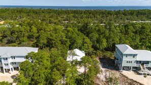 A coastal property with multiple buildings, including a large house with a balcony and a smaller structure. - Fort Morgan House Beach Access 4 Bikes Sleeps 7! (Gulf Shores)