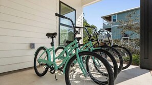 A turquoise bicycle parked on a balcony with a white building in the background. - Fort Morgan House Beach Access 4 Bikes Sleeps 7! (Gulf Shores)