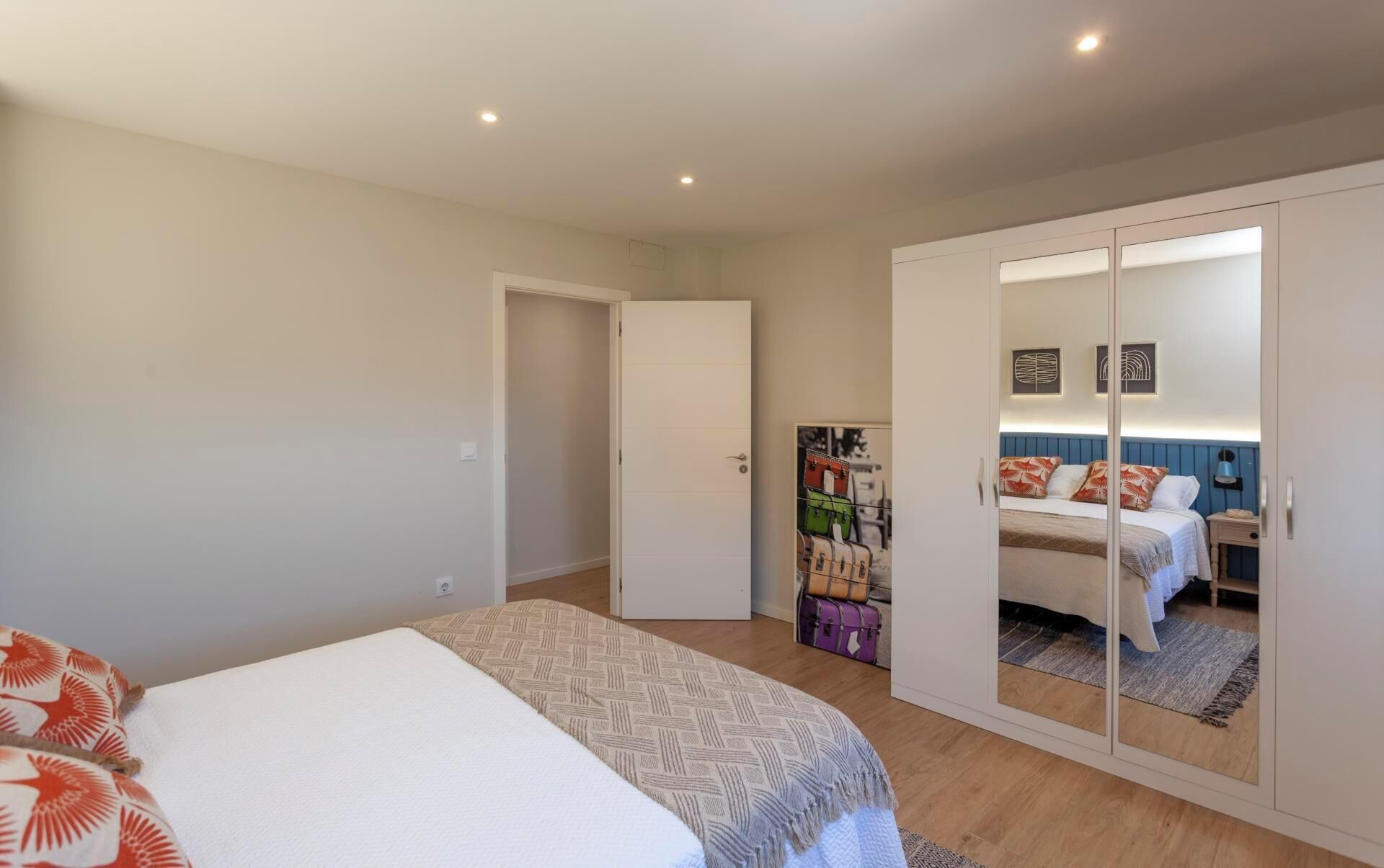 Une chambre à coucher comprenant un lit, une armoire et une porte donnant sur une autre pièce.