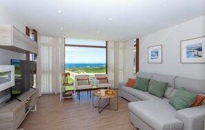 A modern living room with a large window, a sofa, a coffee table, and a TV on a wooden stand.