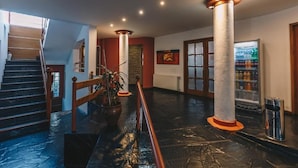 Un vestíbulo amplio con una escalera, una planta en maceta, un refrigerador y una columna.