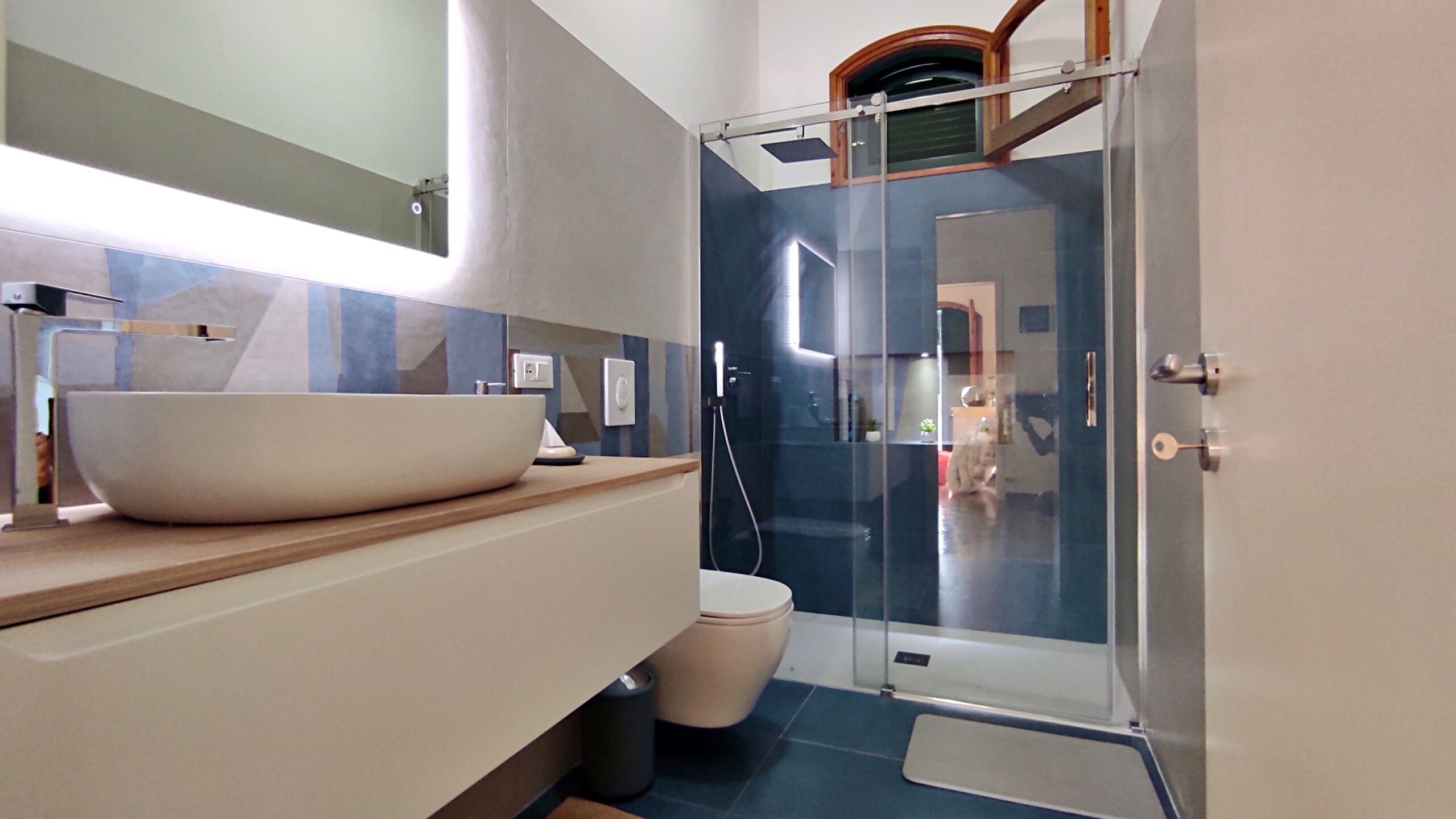 Ein modernes Badezimmer mit einem großzügigen Aufputzwaschbecken, einer Toilette und einer Duschkabine aus Glas.