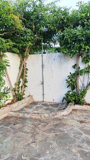 Ein Innenhof mit weißer Mauer, Metallpfosten und Pflanzen.