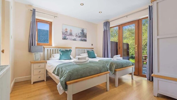 Ein Schlafzimmer mit zwei Betten, einem Fenster, einem Heizkörper und einer Tür zu einem Außenbereich.