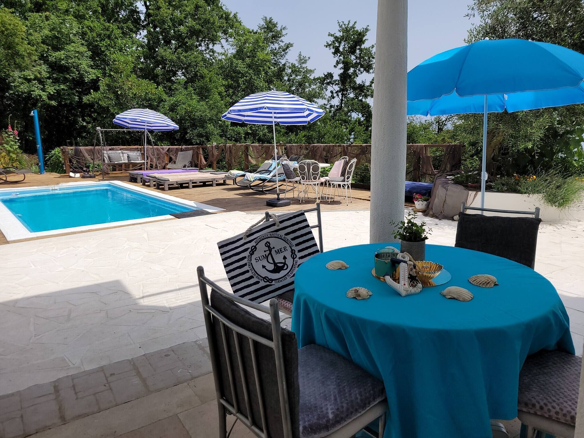 Un espace aménagé au bord de la piscine, avec une table, des chaises et des parasols.