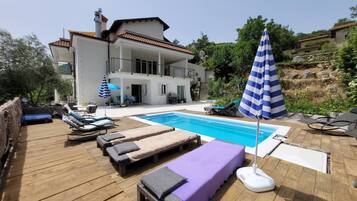 A pool area with lounge chairs and a deck.