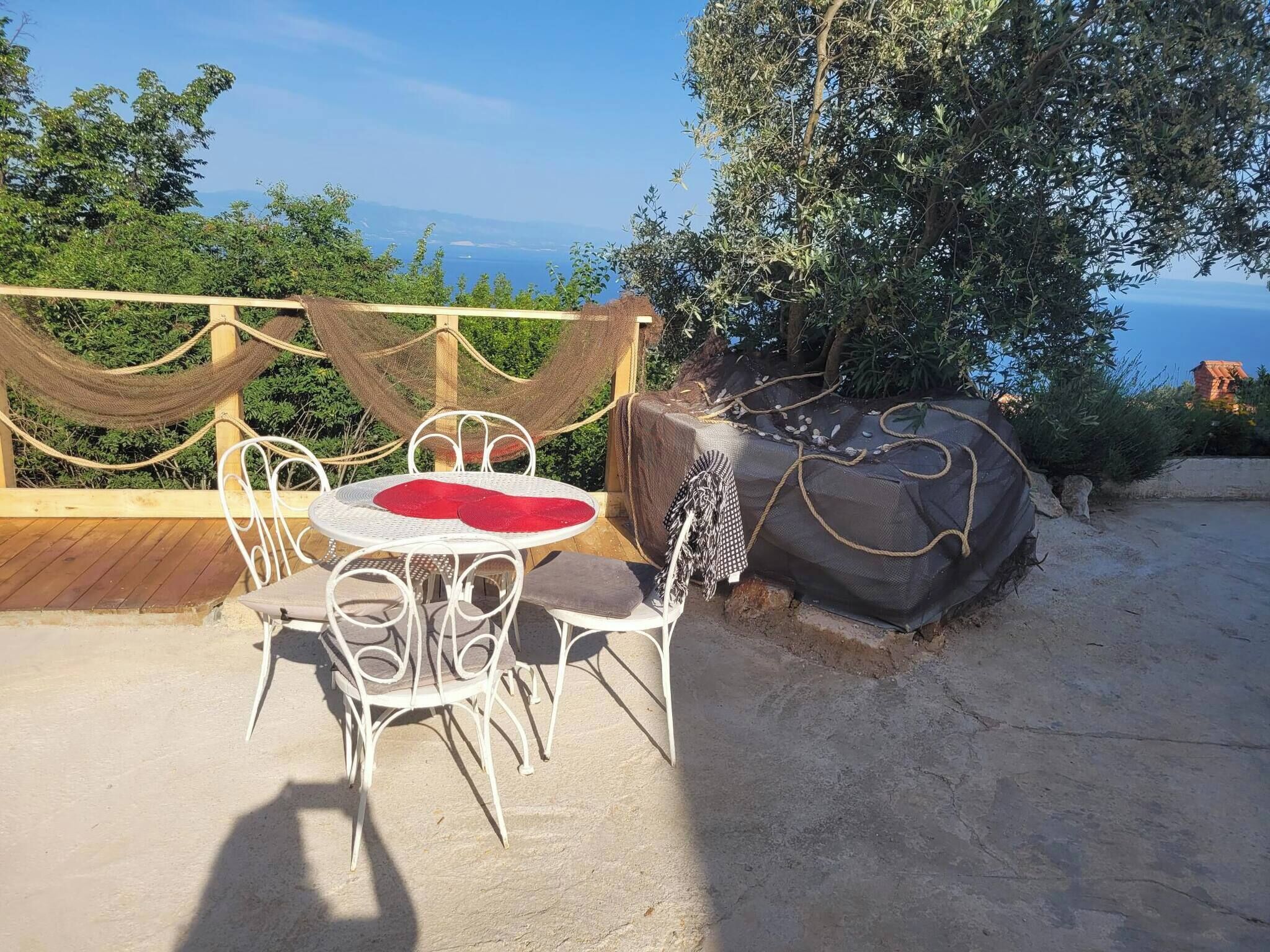 Un patio con una mesa redonda y sillas, una hamaca, y vista al mar.