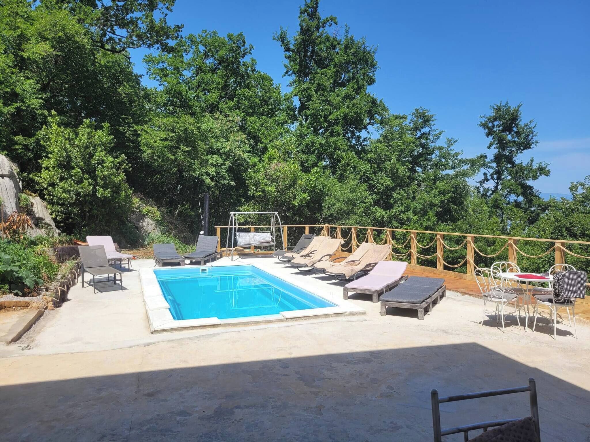 A pool area with lounge chairs and a swing set.
