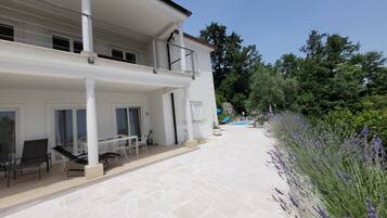 A two-story building with a balcony, a patio with outdoor furniture, and a swimming pool.