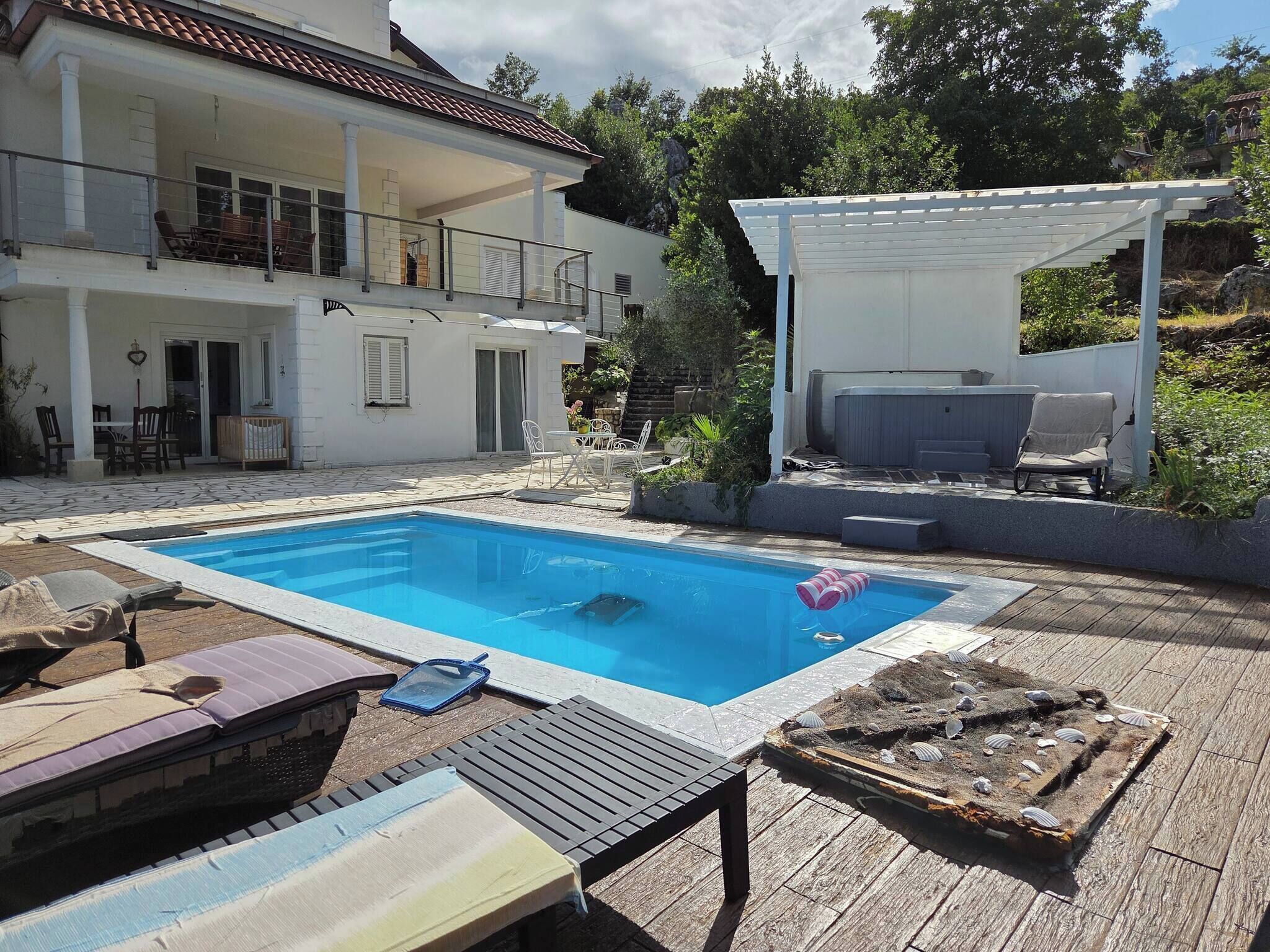 A swimming pool with lounge chairs and a covered seating area.