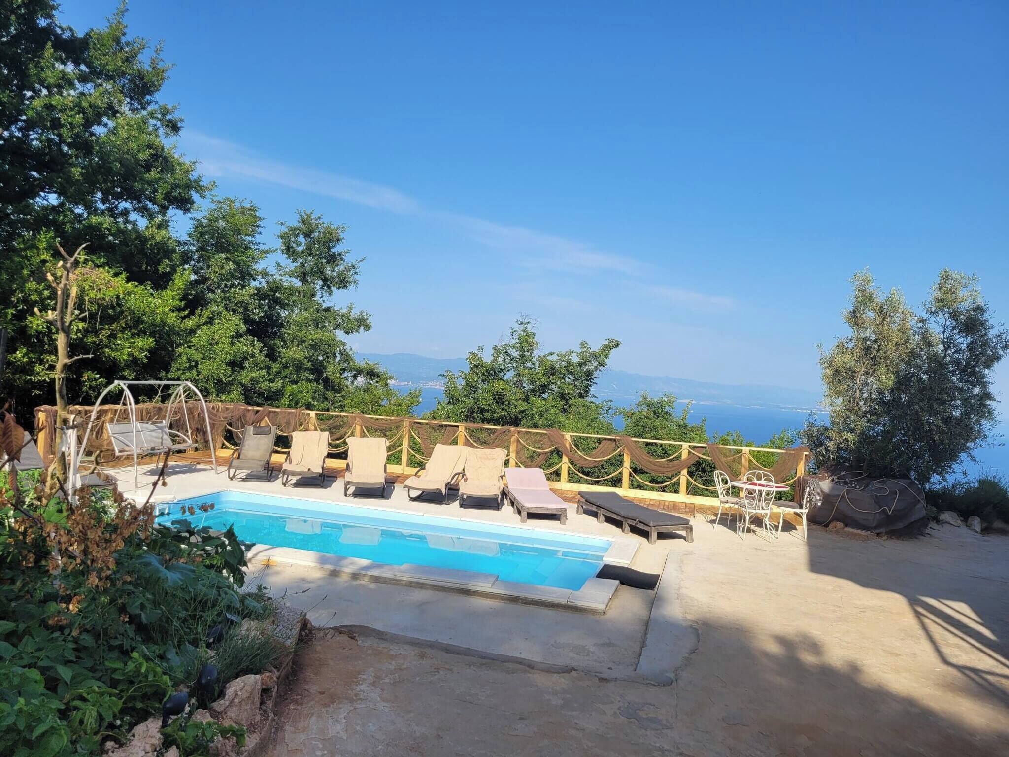 Une piscine avec des chaises longues et vue sur la mer.