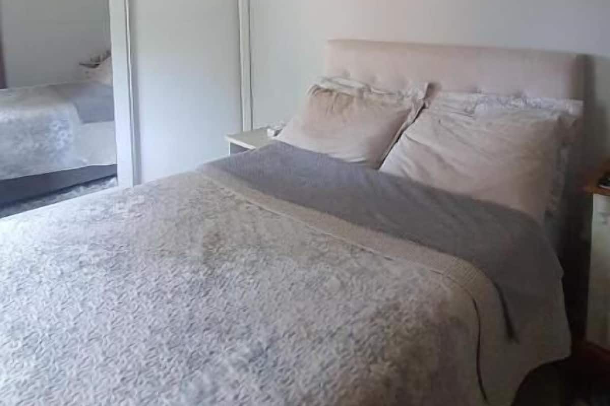 A bedroom with a bed, a ceiling fan, and a large window.