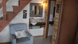 A room with a wooden staircase, a blue armchair, a white sink with a bowl, and a tiled backsplash. - Residencial Pé na Areia Bombinhas (Bombinhas)