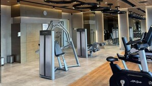 A gym with cardio machines, weightlifting equipment, and a wooden floor. - Sky Suite-City Sunset & River views (Mandaluyong City)