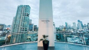 A modern hotel with a prominent column labeled 'NOVOTEL SUITES' and a view of a cityscape with high-rise buildings. - Sky Suite-City Sunset & River views (Mandaluyong City)