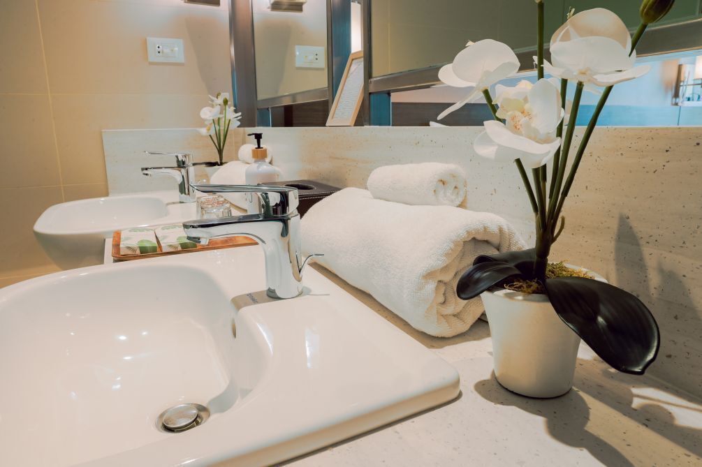 Ein Badezimmer mit Waschbecken, Spiegel, Handtuch und einer Topfpflanze.