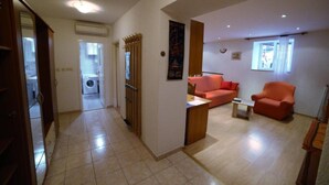 Ein Wohnzimmer mit Sofa, Sesseln, Couchtisch und einem fenster mit Vorhängen.
