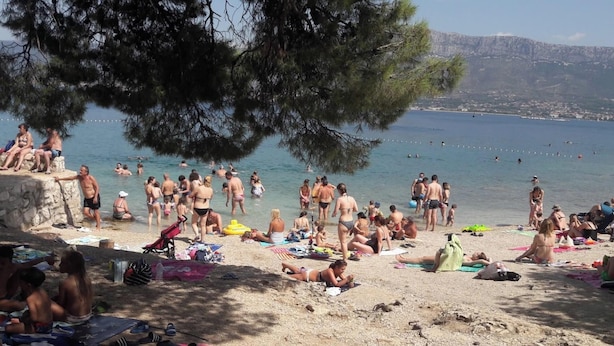 Ein überfüllter Strand mit Menschen, die sich sonnen und schwimmen.