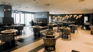Un restaurant modern amb taules i caires rodones, un sostre amb disseny i una paret decorada amb ornaments circulars.