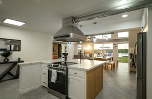 Eine moderne Küche mit Kochinsel, integriertem Backofen und Edelstahl-Dunstabzugshaube.