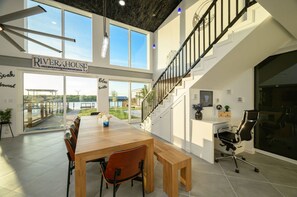 A spacious room with a large wooden table, a bench, and a staircase.