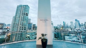A modern hotel with a prominent column labeled 'NOVOTEL SUITES' and a view of a cityscape with high-rise buildings. - Cozy Private Room w King (Mandaluyong City)
