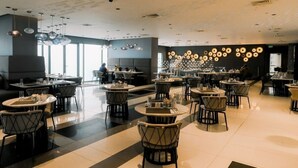 Un restaurant moderne avec des tables et des chaises rondes, un plafond orné de motifs et un mur décoré de motifs circulaires.