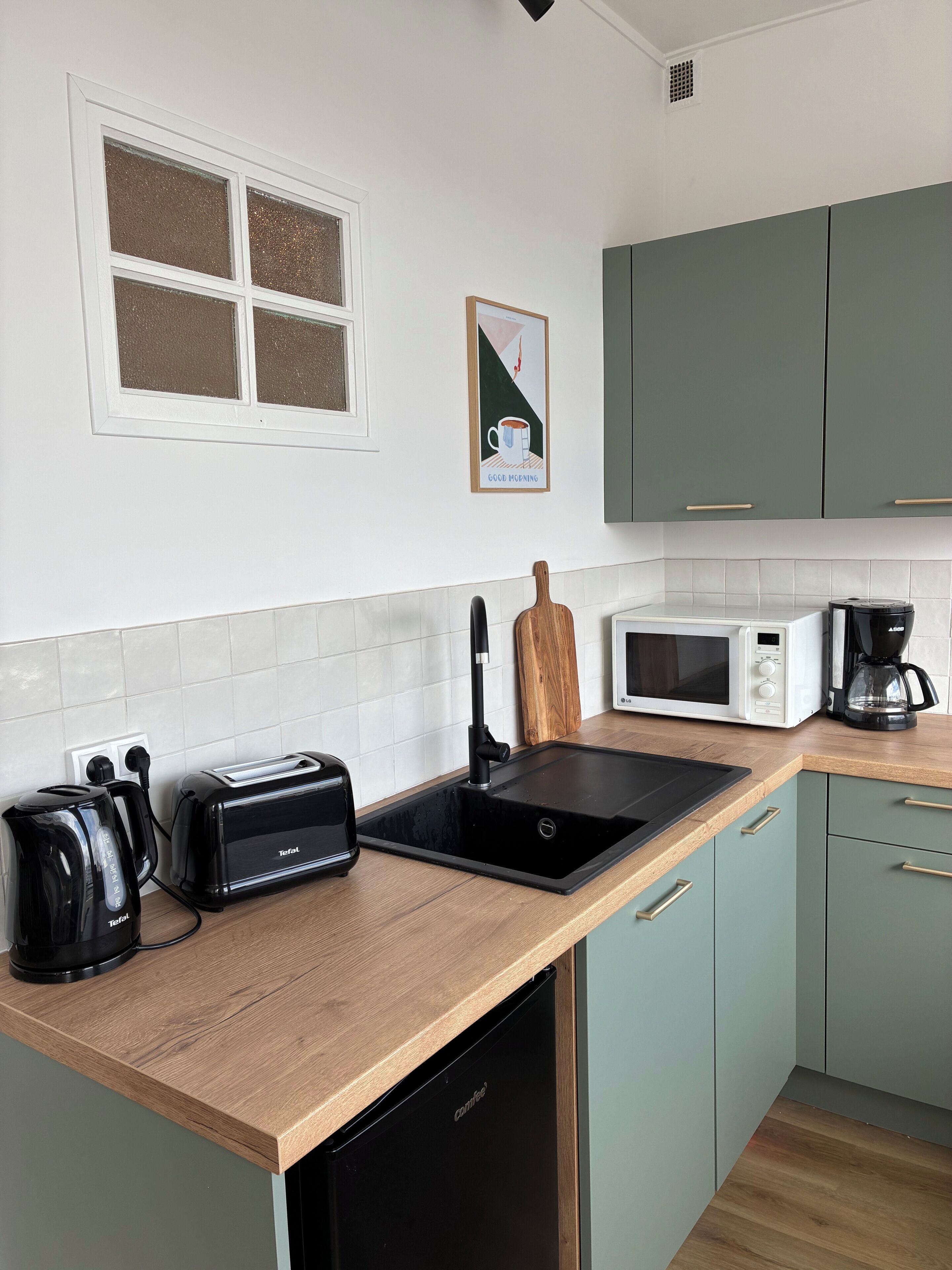 A kitchen with a microwave, toaster, coffee maker, and a sink.