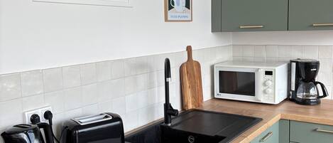 A kitchen with a microwave, toaster, coffee maker, and a sink.