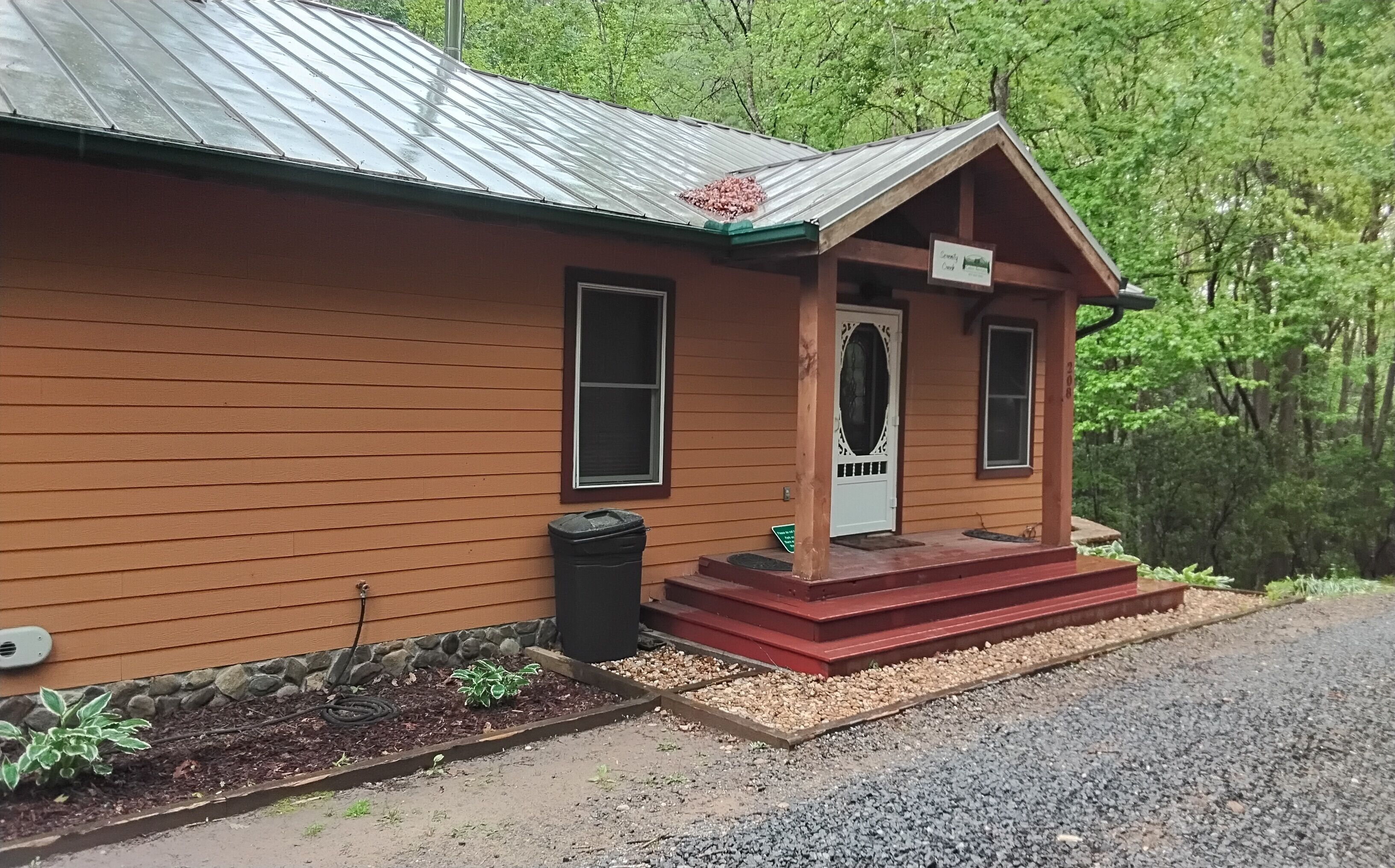 A wooden cabin with a metal roof, a front door, and a small porch.