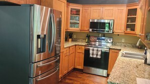 A kitchen with wooden cabinets, stainless steel appliances, granite countertops, and a wooden ceiling with pendant lights. - Creekside serenity in murphy (Murphy)