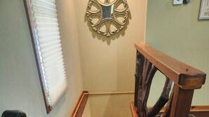 A wooden staircase with a unique design, including a branch-like handrail and a wall-mounted decorative mirror. - Creekside serenity in murphy (Murphy)