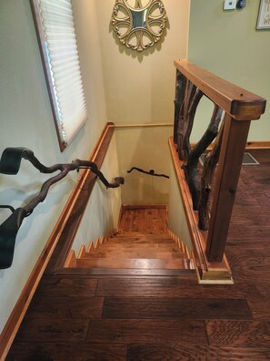 Eine Holztreppe mit einem außergewöhnlichen Design, einschließlich eines astförmigen Geländers und eines an der Wand befestigten Ziertspiegels.