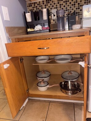 A kitchen with a wooden cabinet, a coffee maker, and various kitchen utensils. - 2-bedroom condo on beach Blv by Jaguar Stadium with two pools (Jacksonville)