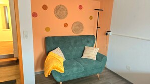 A teal sofa with two pillows, a yellow throw blanket, and a wall with circular decorations.