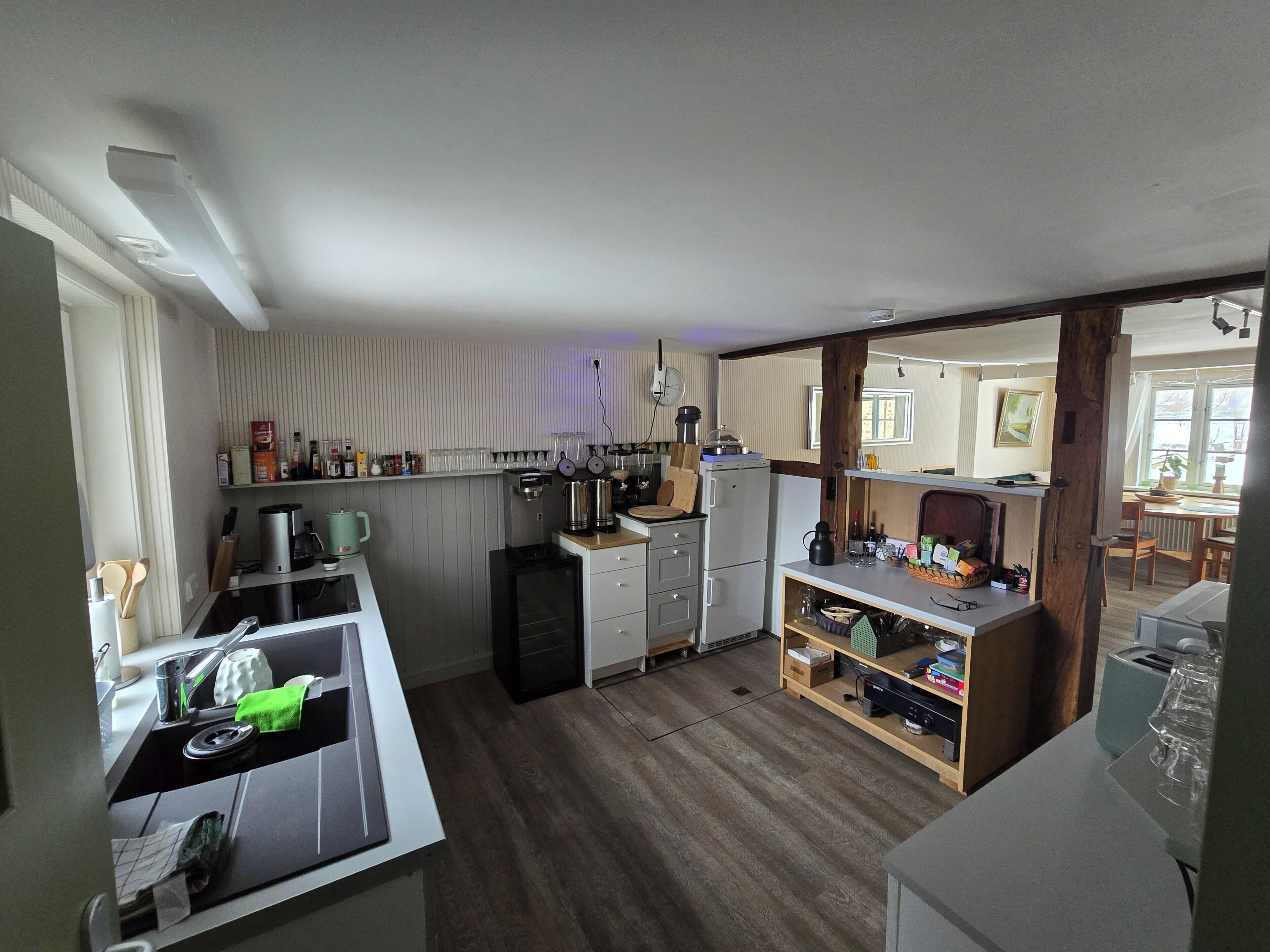 A compact kitchen with a coffee machine, kettle, and a small refrigerator.