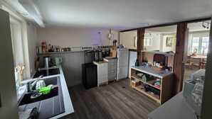 A compact kitchen with a coffee machine, kettle, and a small refrigerator.
