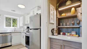 Una cocina moderna con armarios blancos, electrodomésticos de acero inoxidable y encimera de madera.