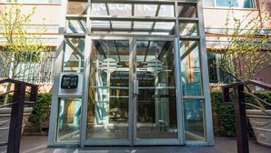 Una entrada moderna a un edificio con puerta giratoria de vidrio y sistema de seguridad por teclado.